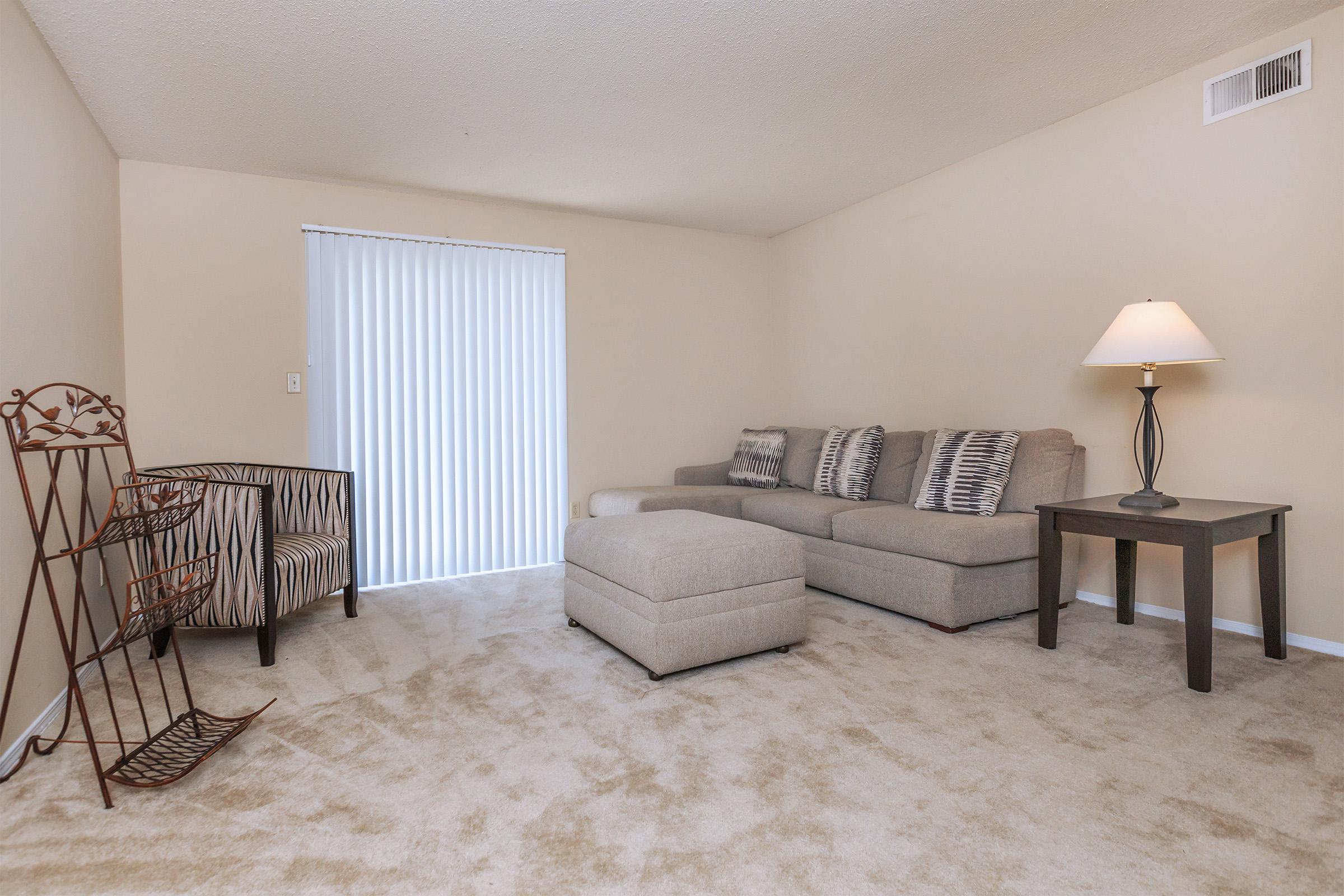 Living room with beige carpet, couch, and lamp.