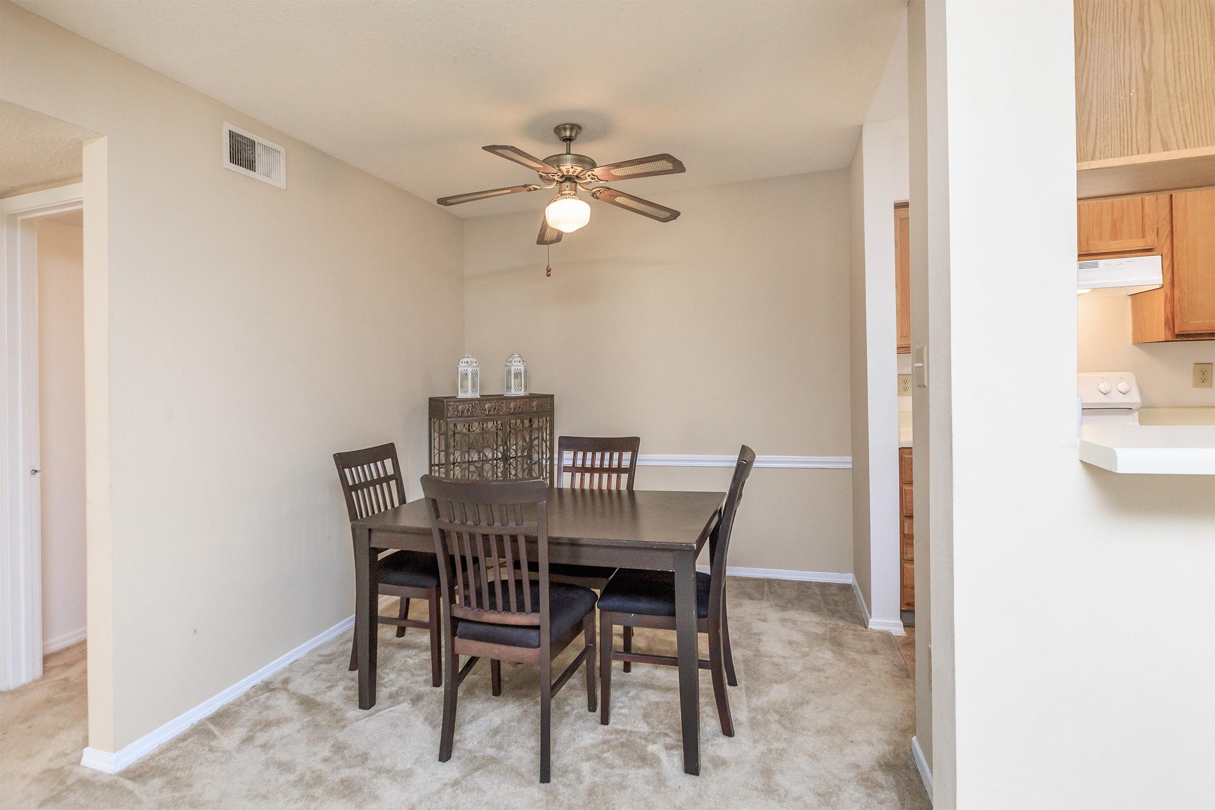 Dining area with table, chairs, and ceiling fan.
