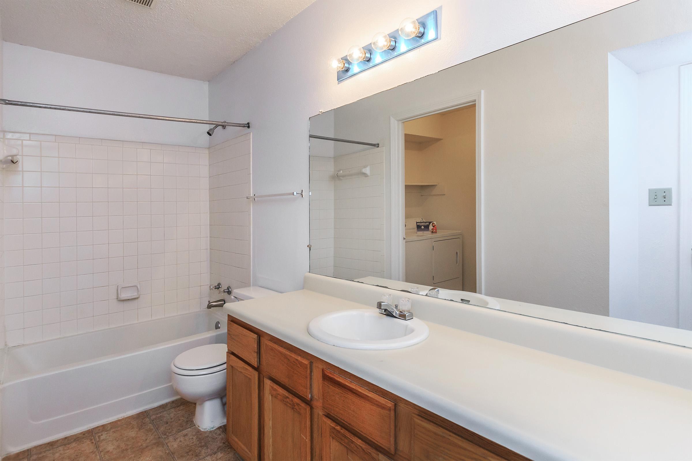 Bathroom with a large mirror and white tiled shower.