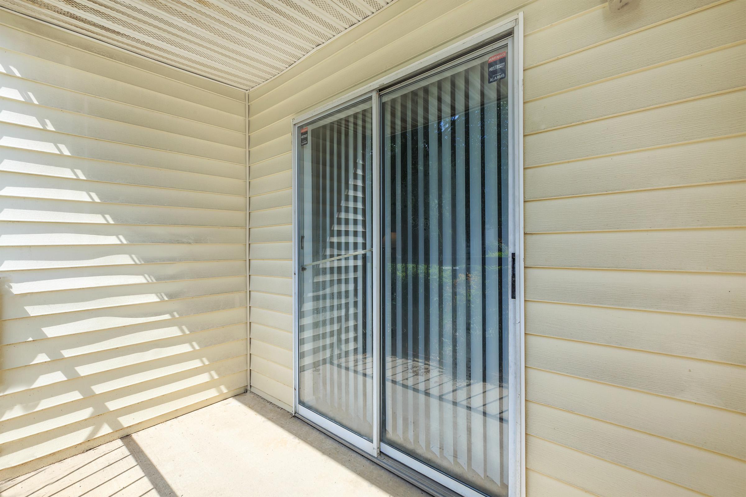 Private balcony with sliding glass door and siding walls.