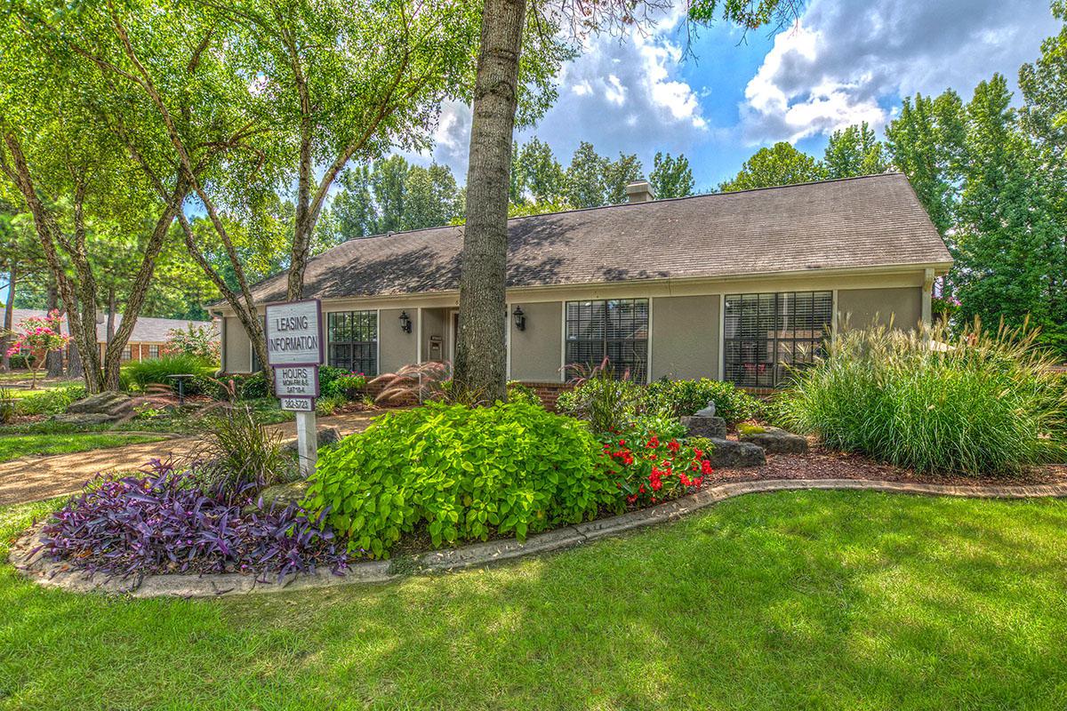 Clubhouse surrounded by trees and well-kept landscaping.