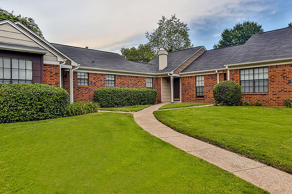 Exterior view of brick buildings and green lawn.