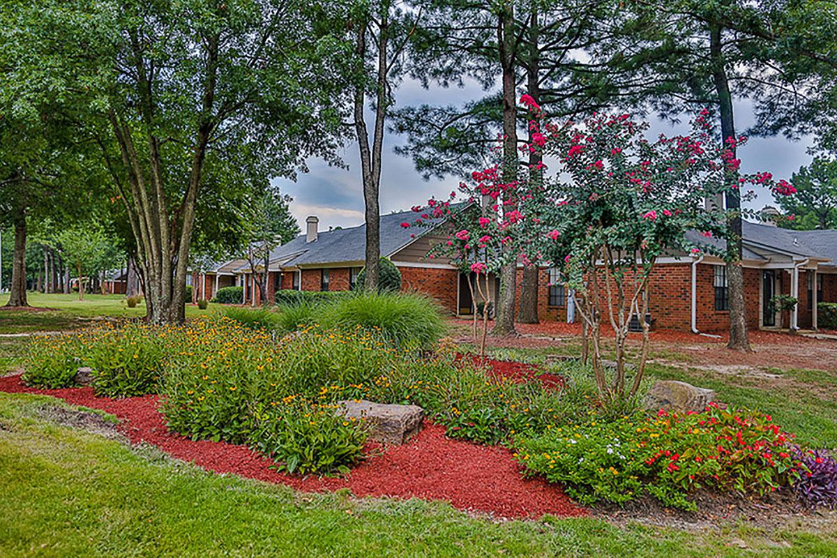 Brick apartment buildings with vibrant flowerbeds.