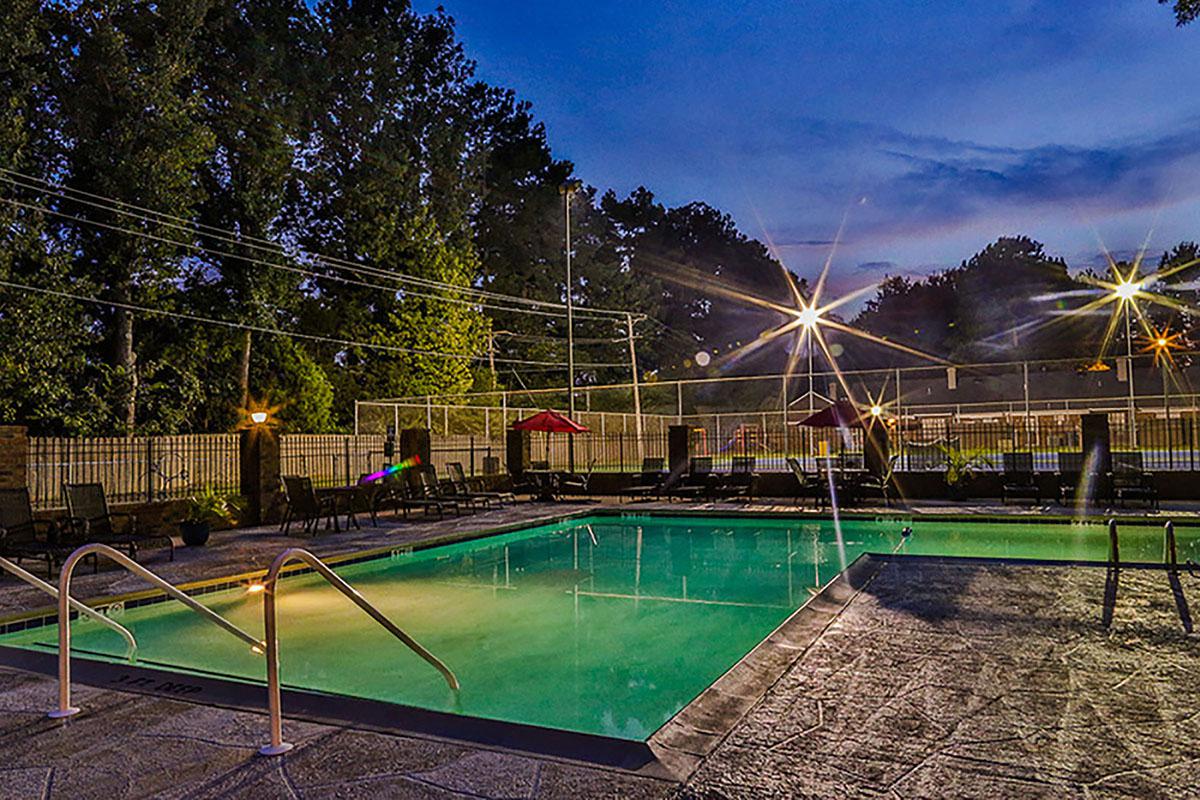 Night view of pool surrounded by trees and peaceful ambiance.