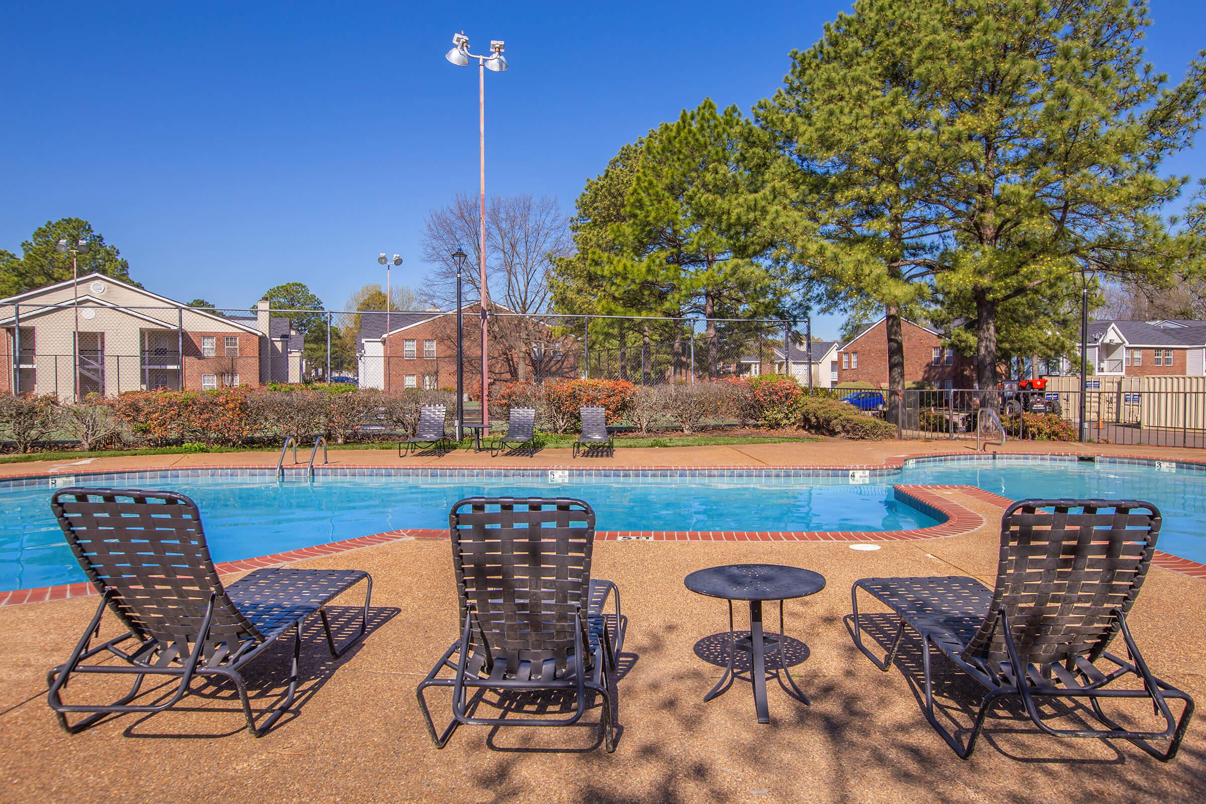 Poolside lounge chairs with small tables near the pool.