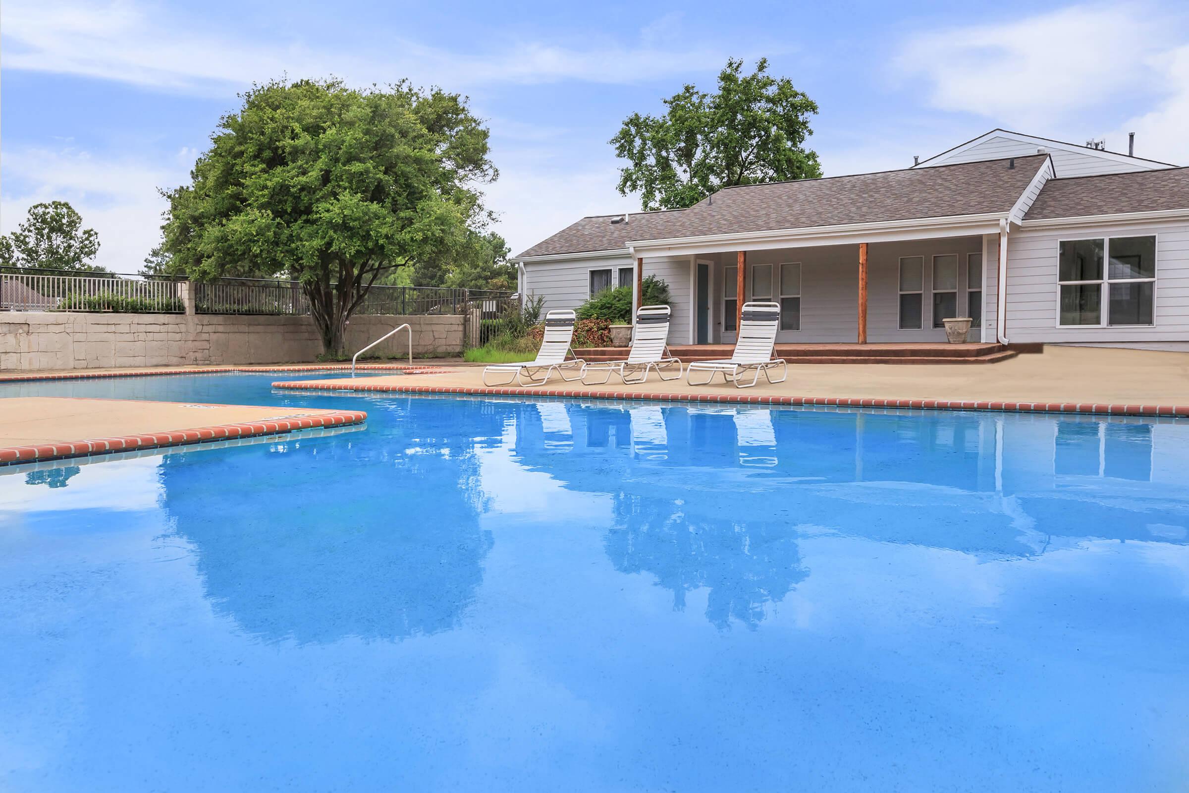 Apartment pool area surrounded by greenery.