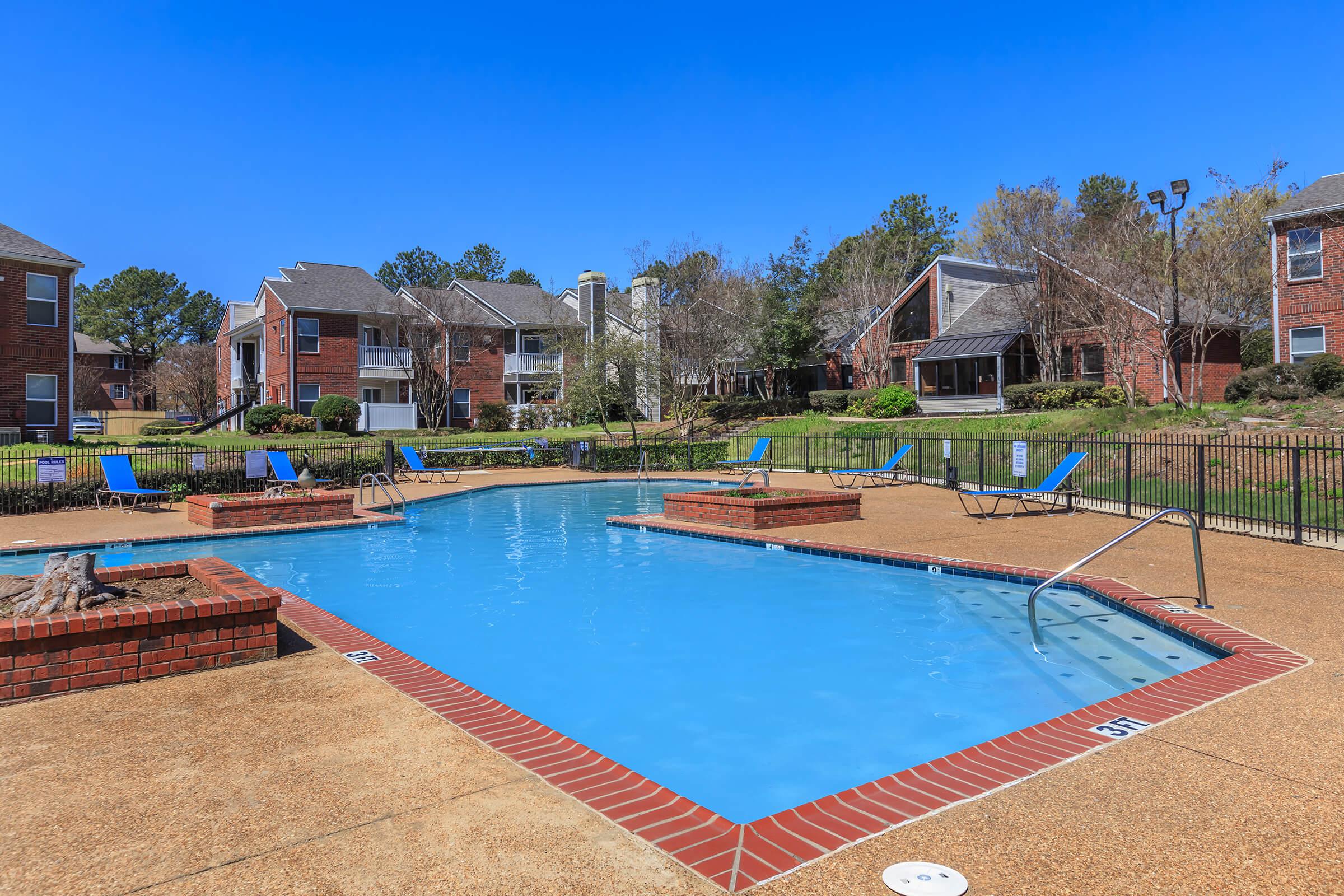 Poolside view of apartments with brick and siding exteriors.