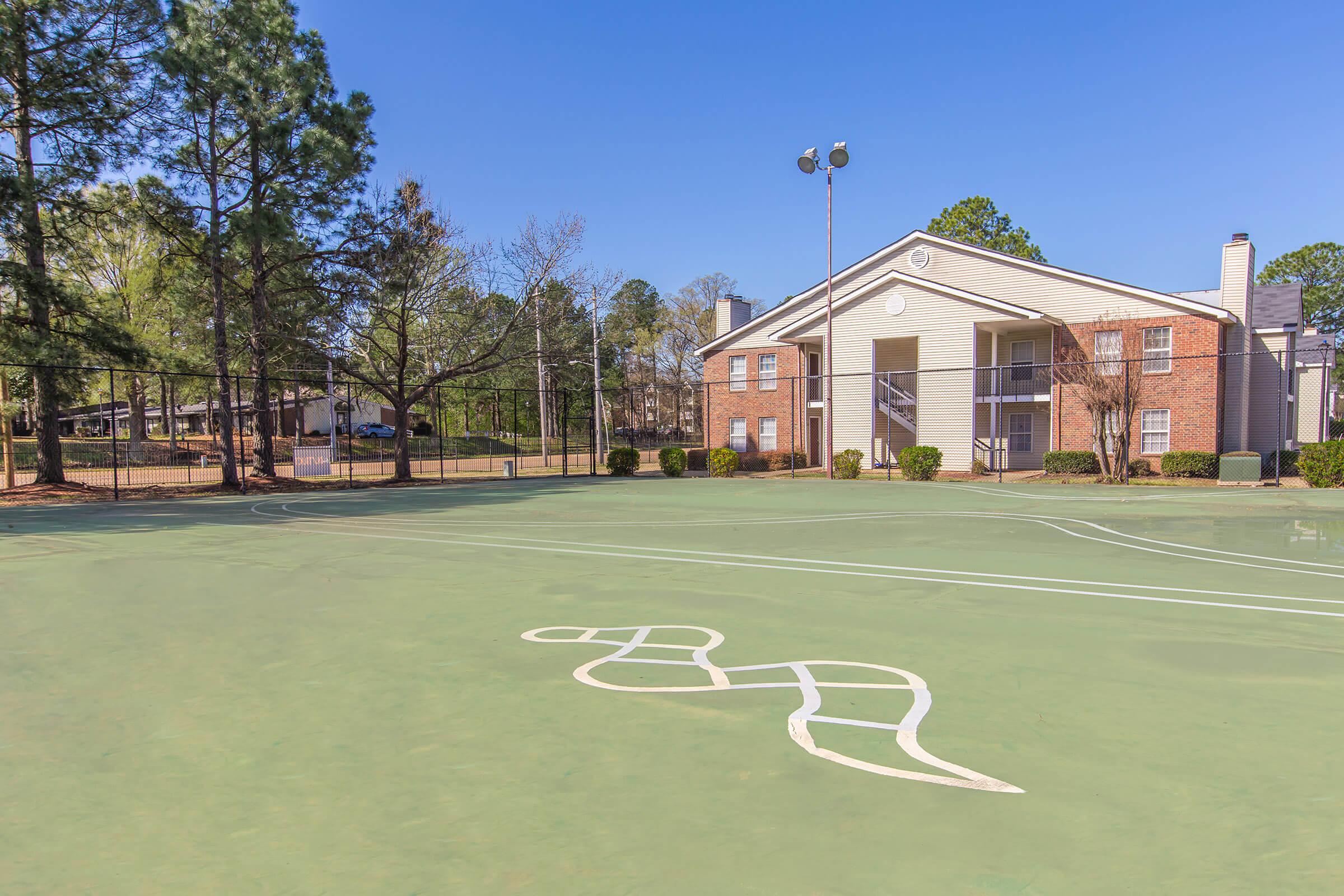 Open lawn area with fitness track and apartment buildings.
