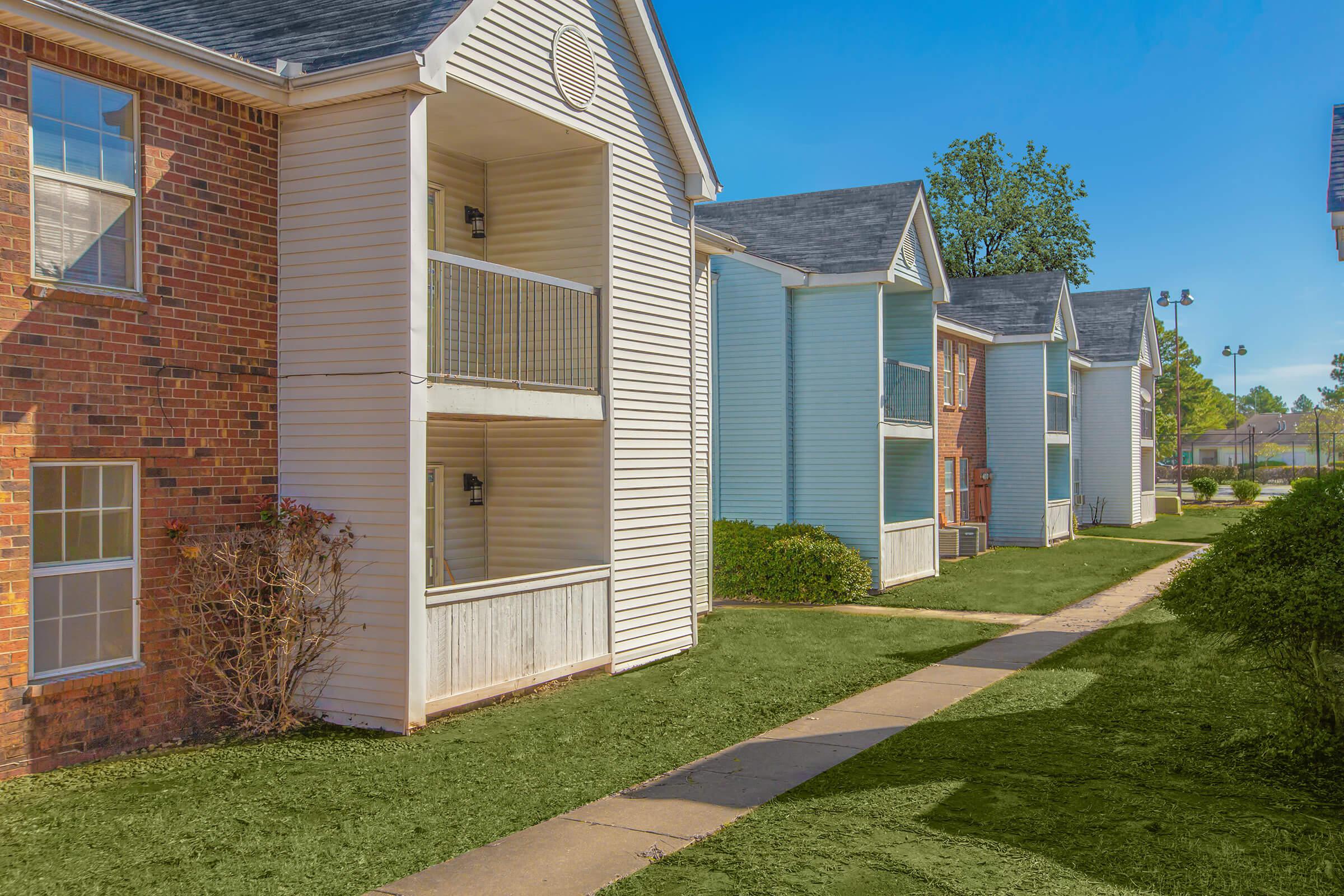Apartments with white siding and landscaped front yards.