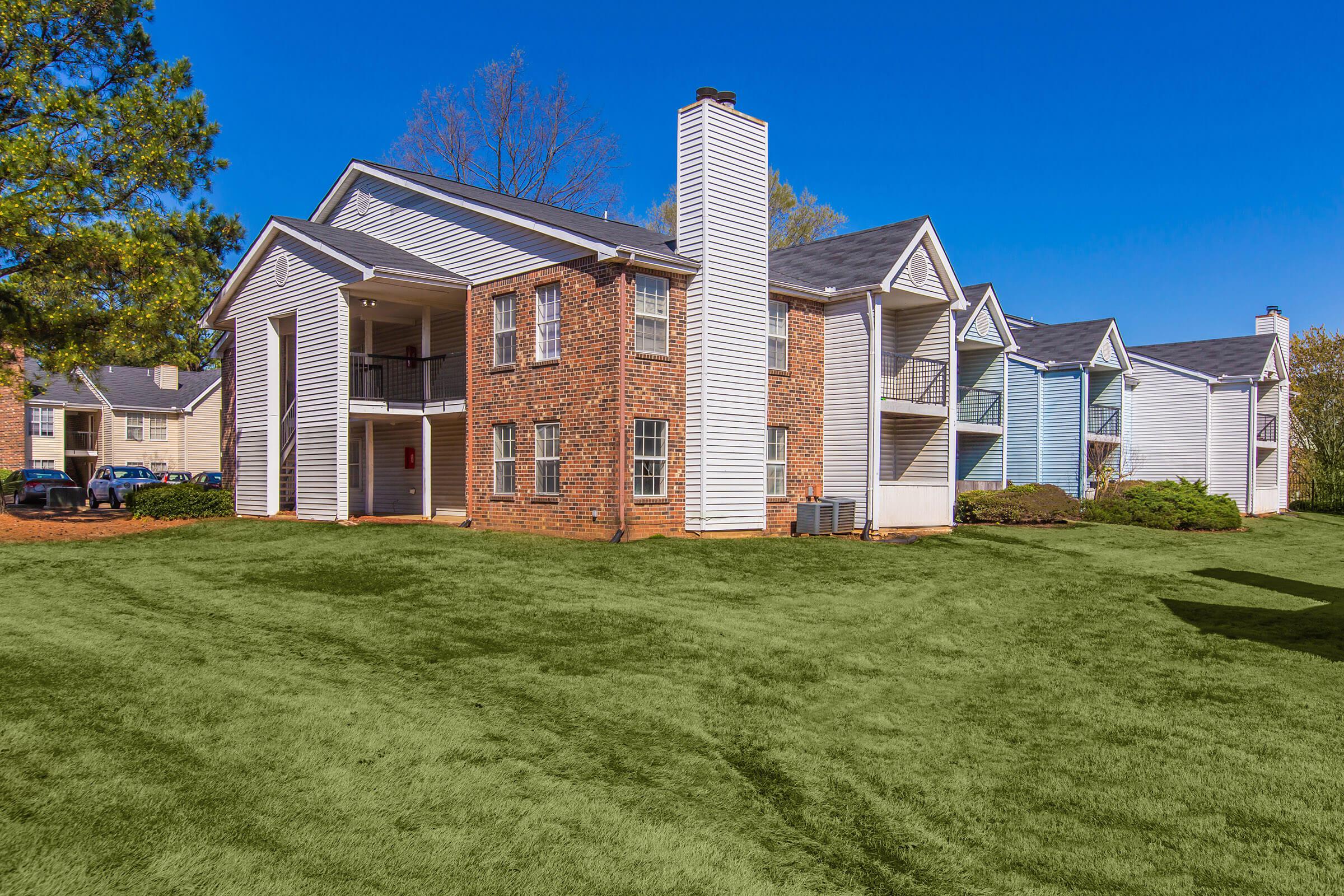 Apartment complex with greenery and mature trees.