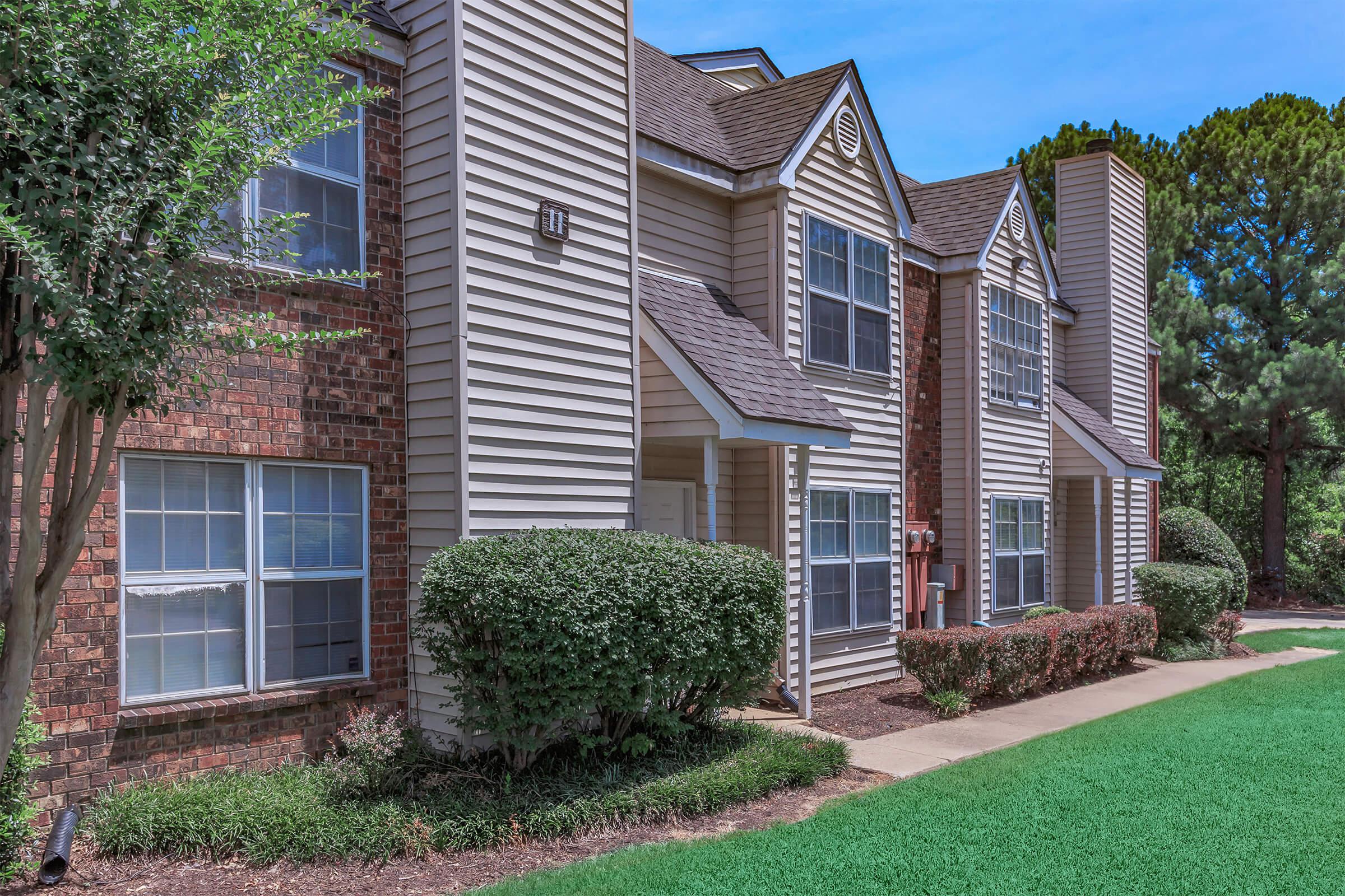 Close-up view of apartments with white siding and brick accents.