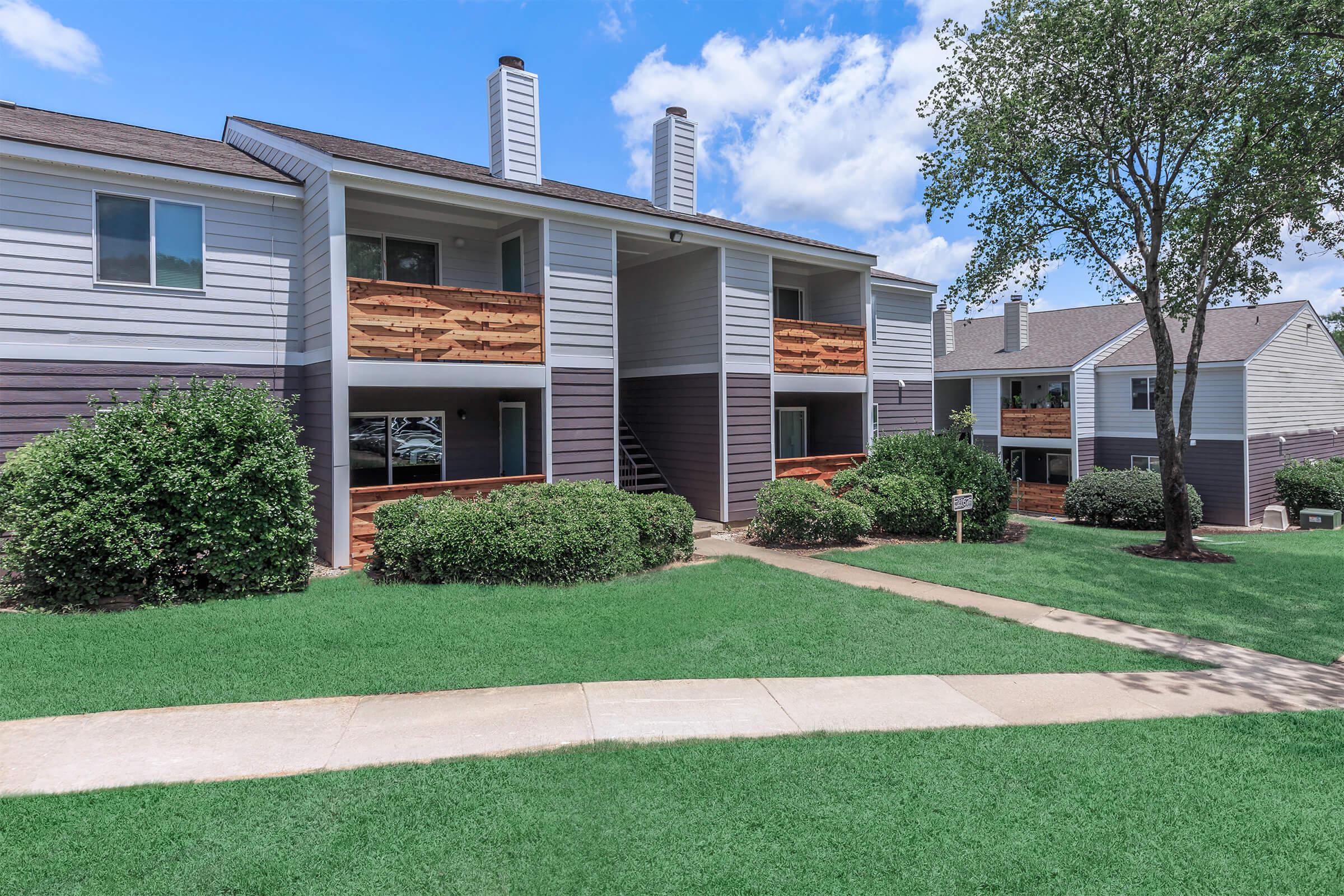 Apartment exterior with pathway and shrubs.