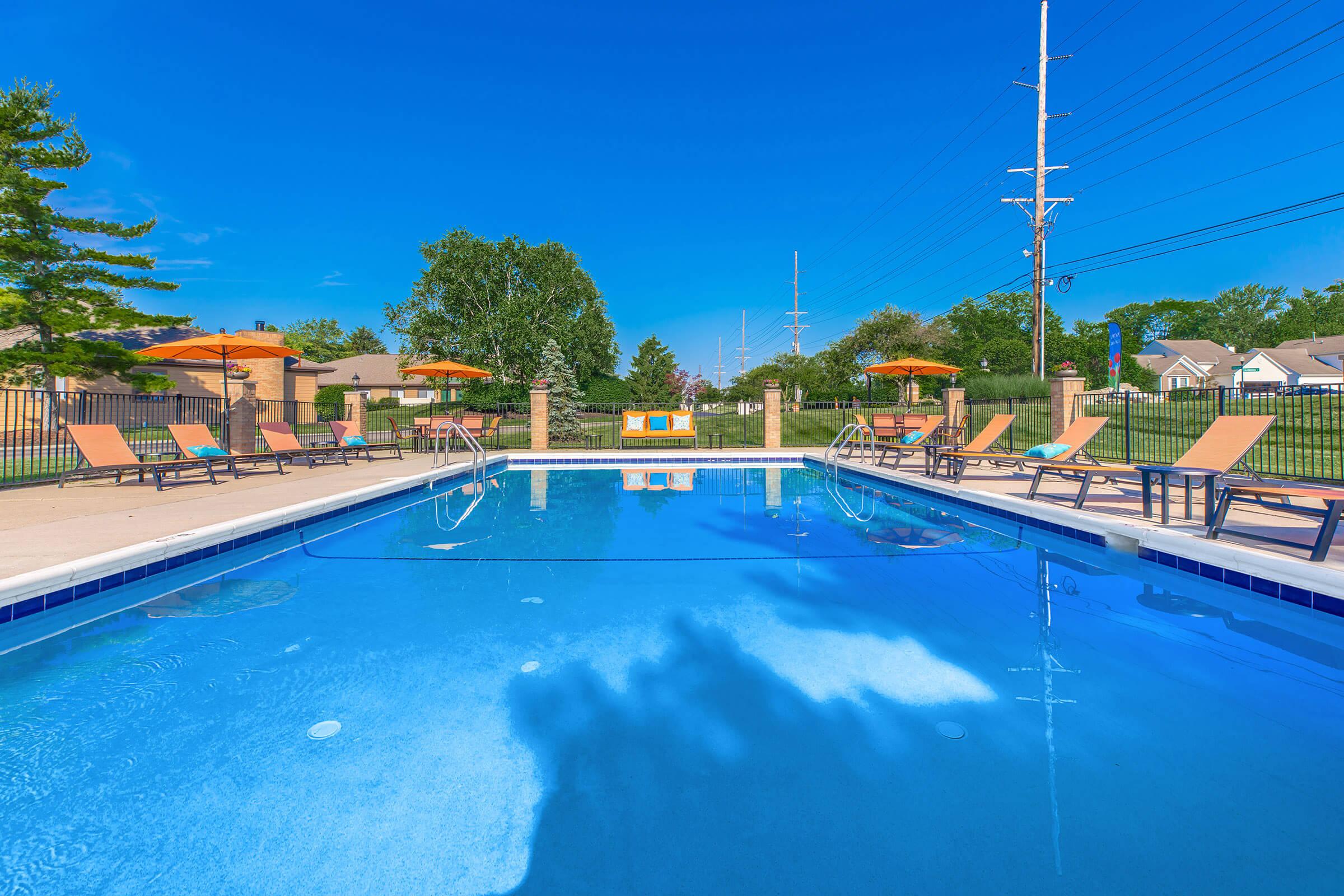 Outdoor pool with lounge chairs and a clear blue sky