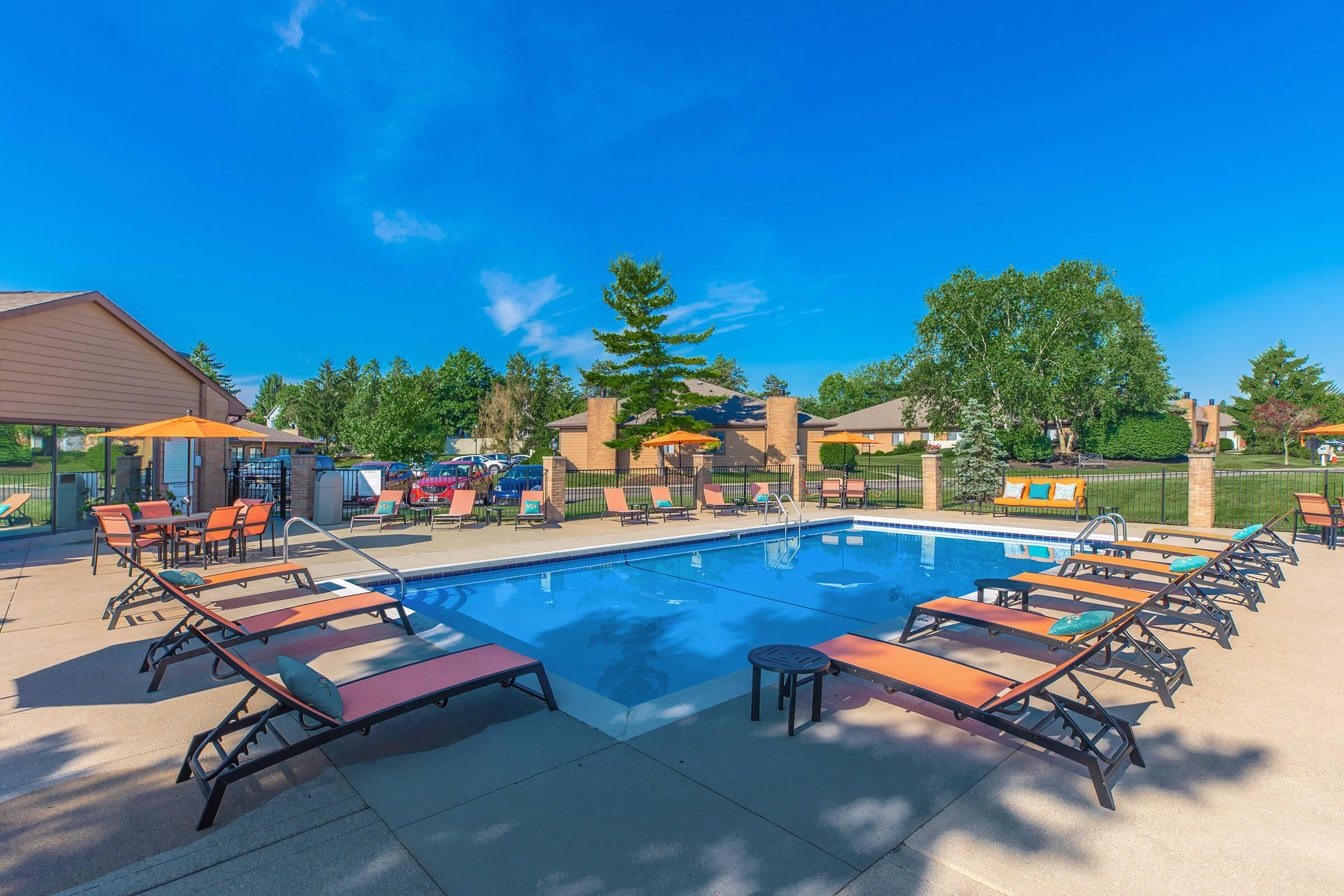 Poolside lounge chairs and tables near the pool.