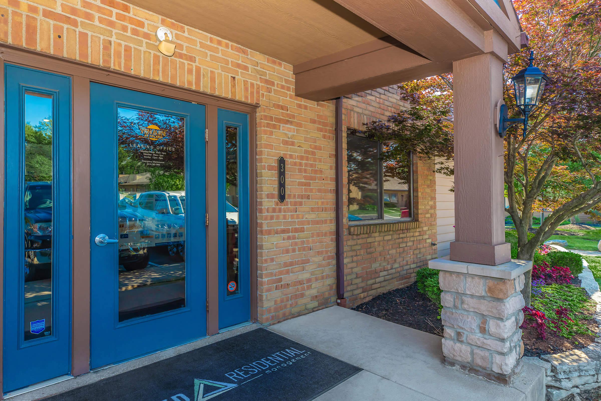 Entrance to a building with blue doors and stone pillars.