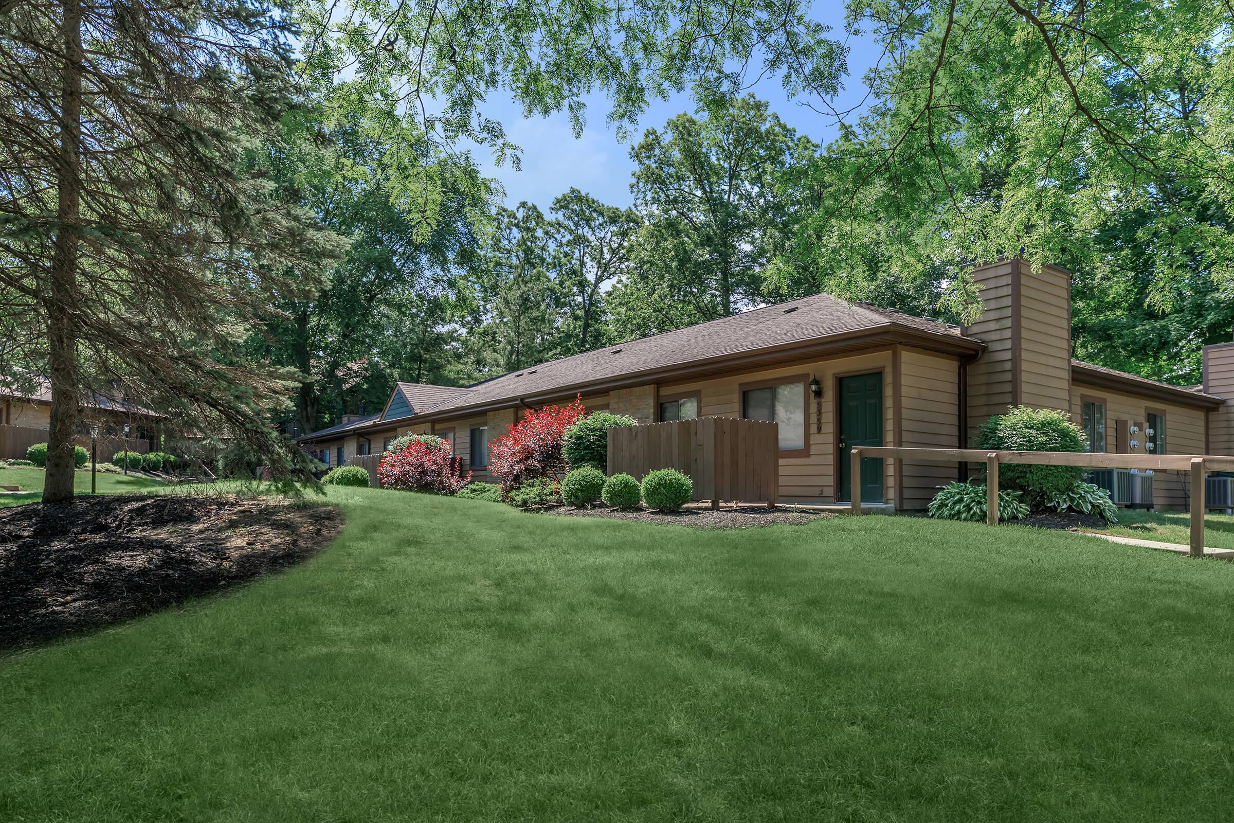 Large green lawn with brown 1 story building.