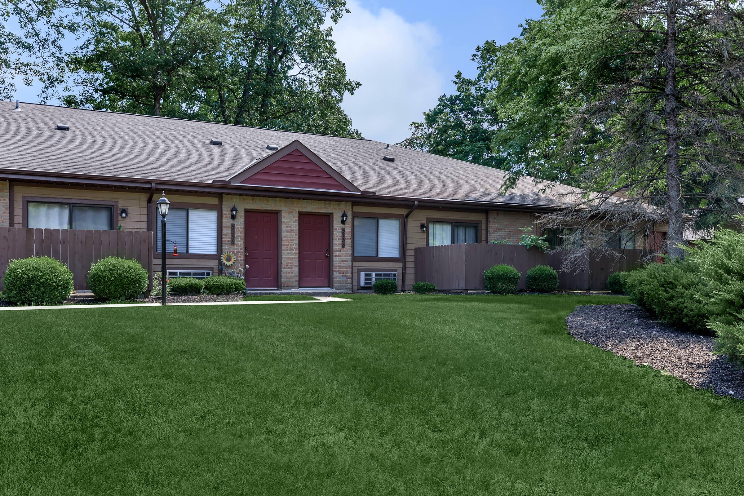 Big green lawn with building and red front doors.