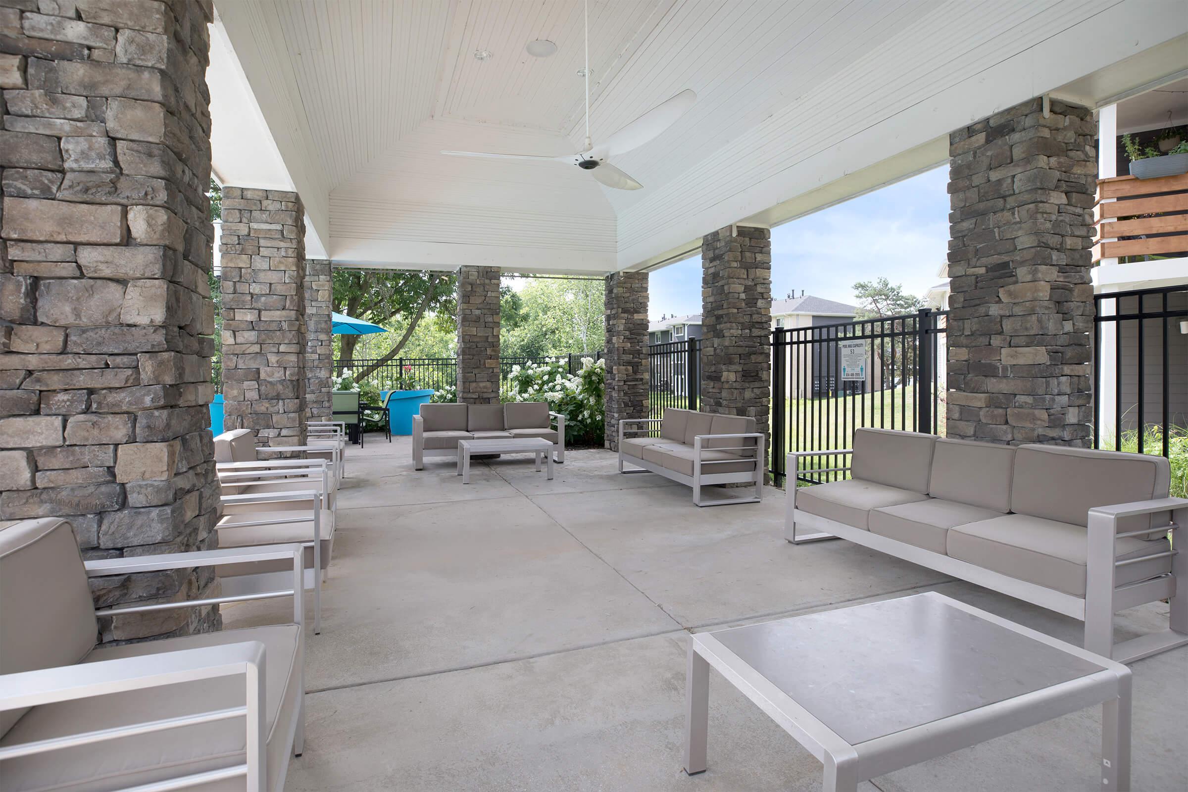 Covered seating area with stone pillars near the pool.