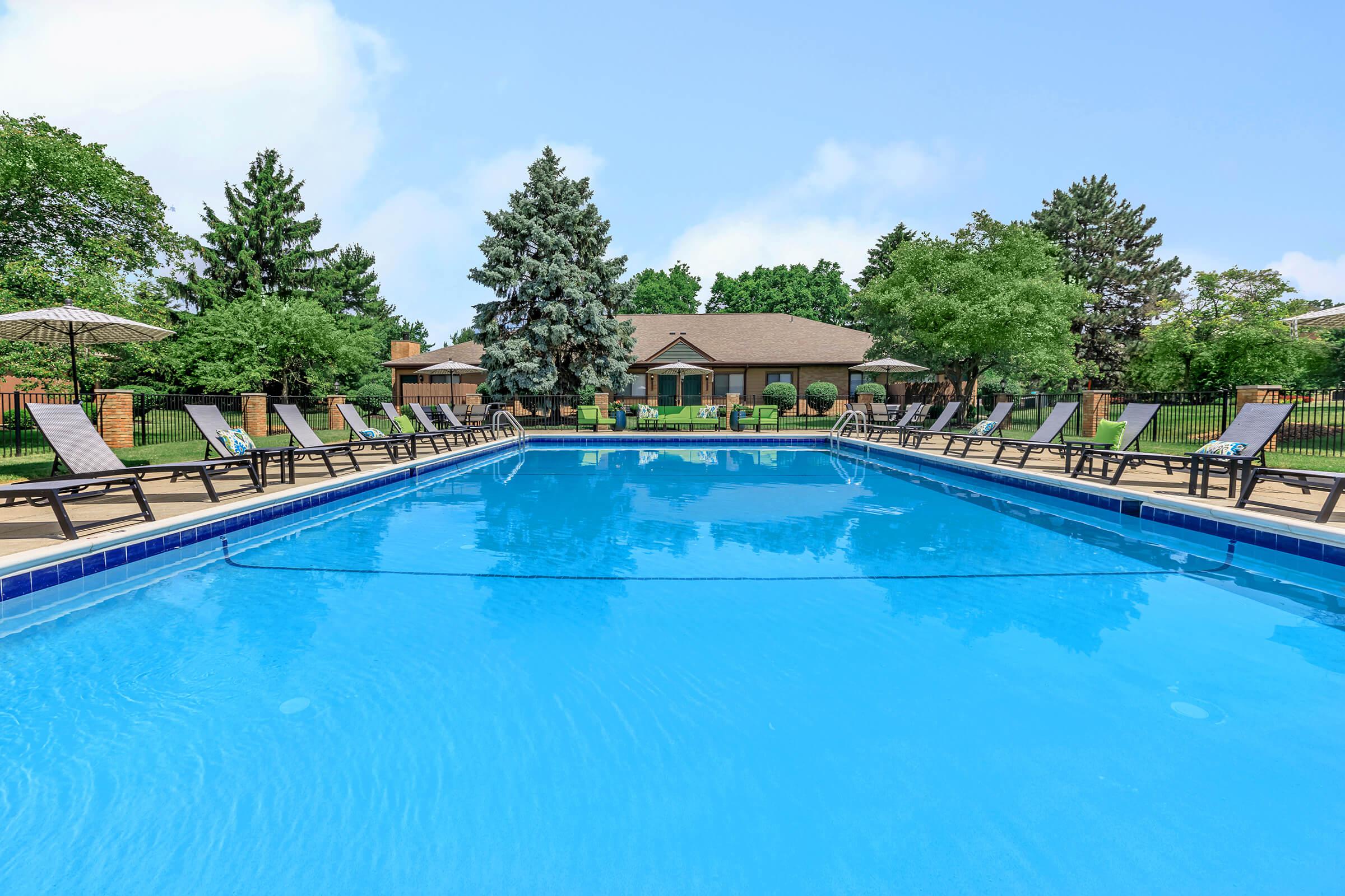 Poolside lounge area with trees in the background.