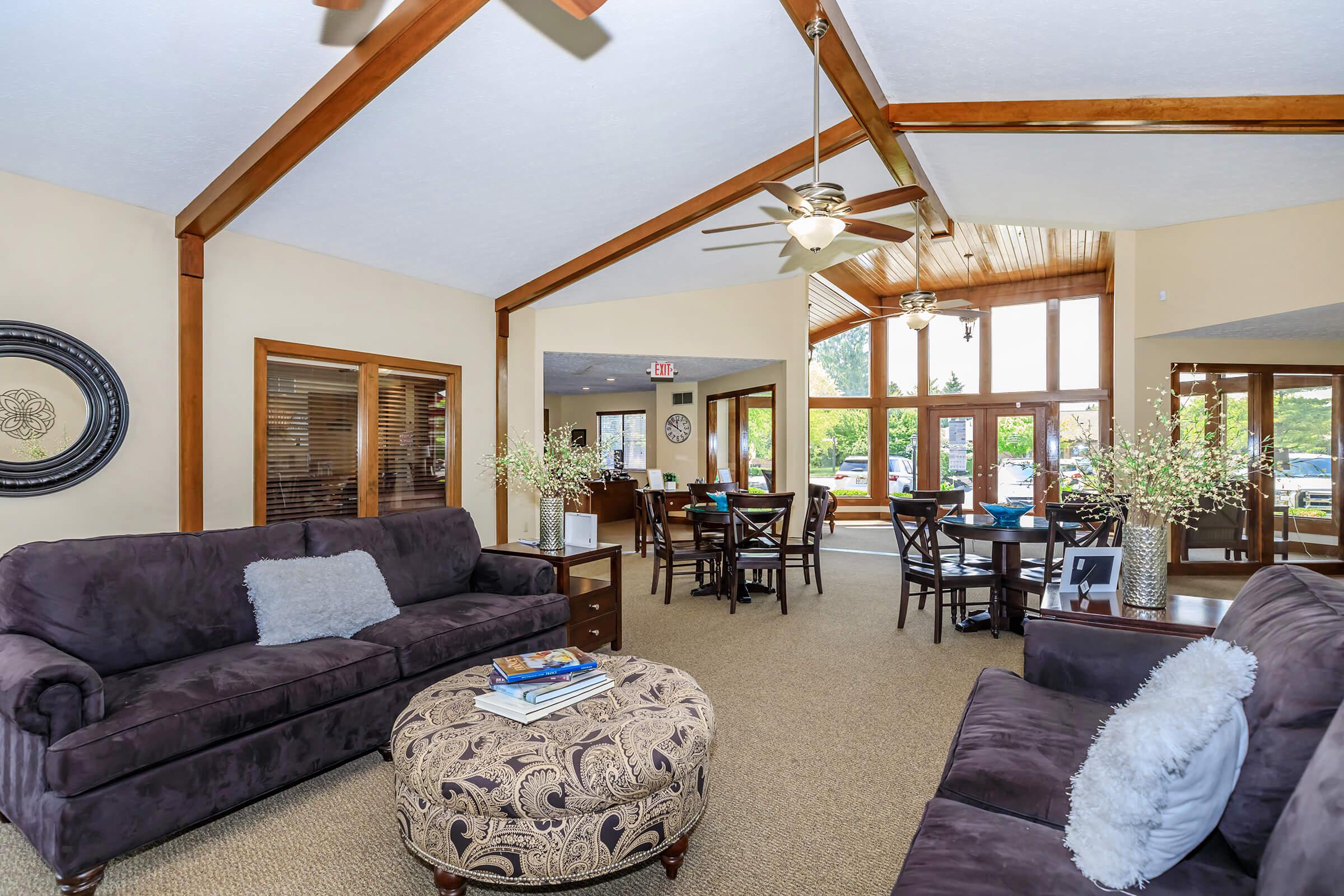 Living room with dark couches and large windows.