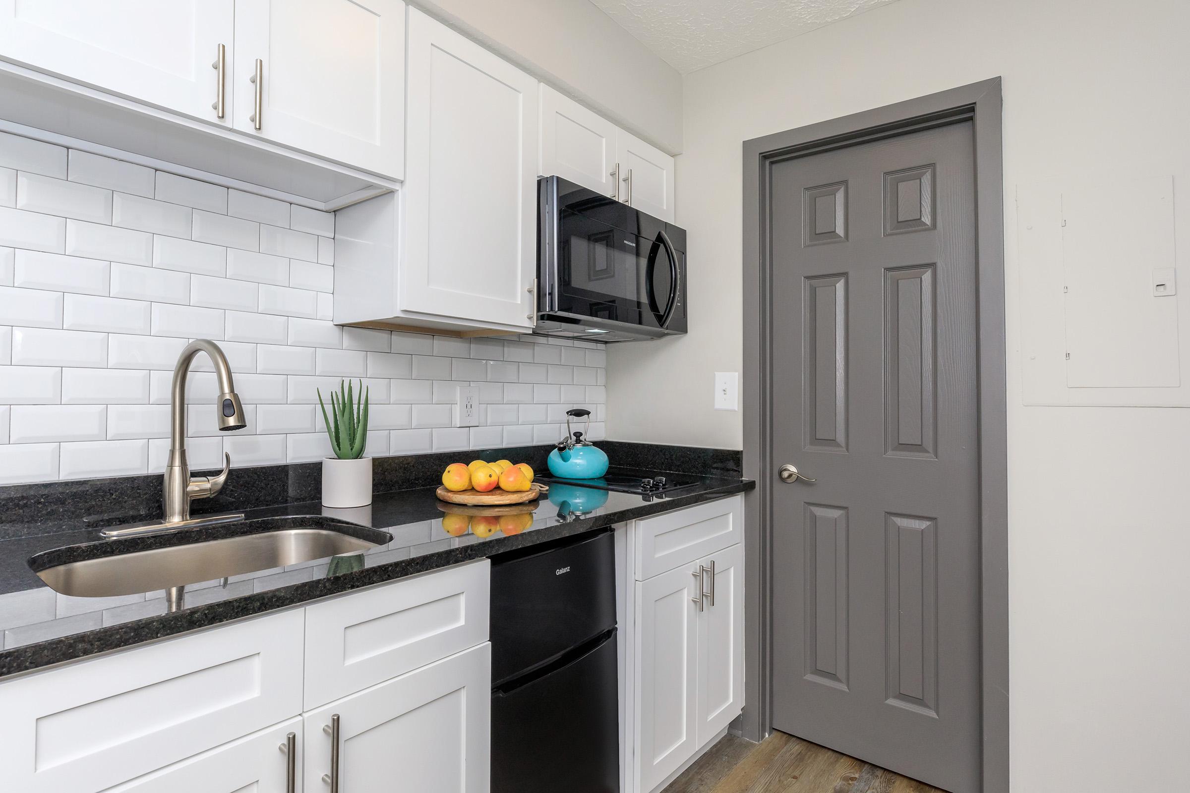 Modern kitchen with white cabinets and black countertops.