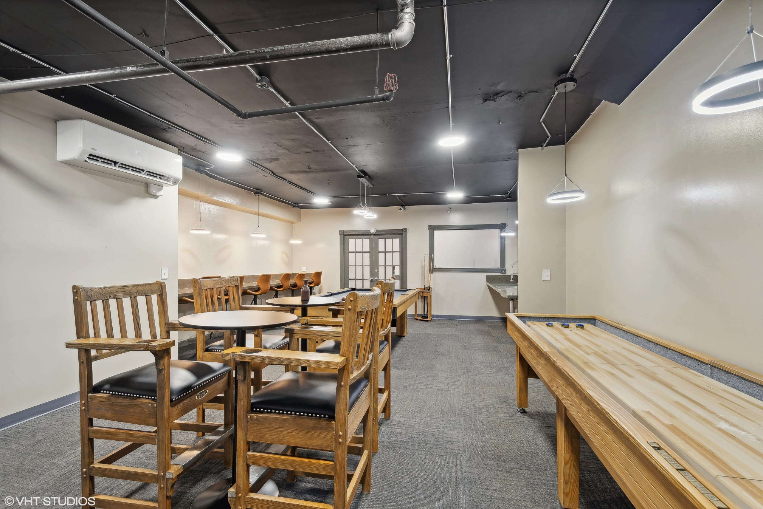 Community room with tables, chairs, and modern lighting.